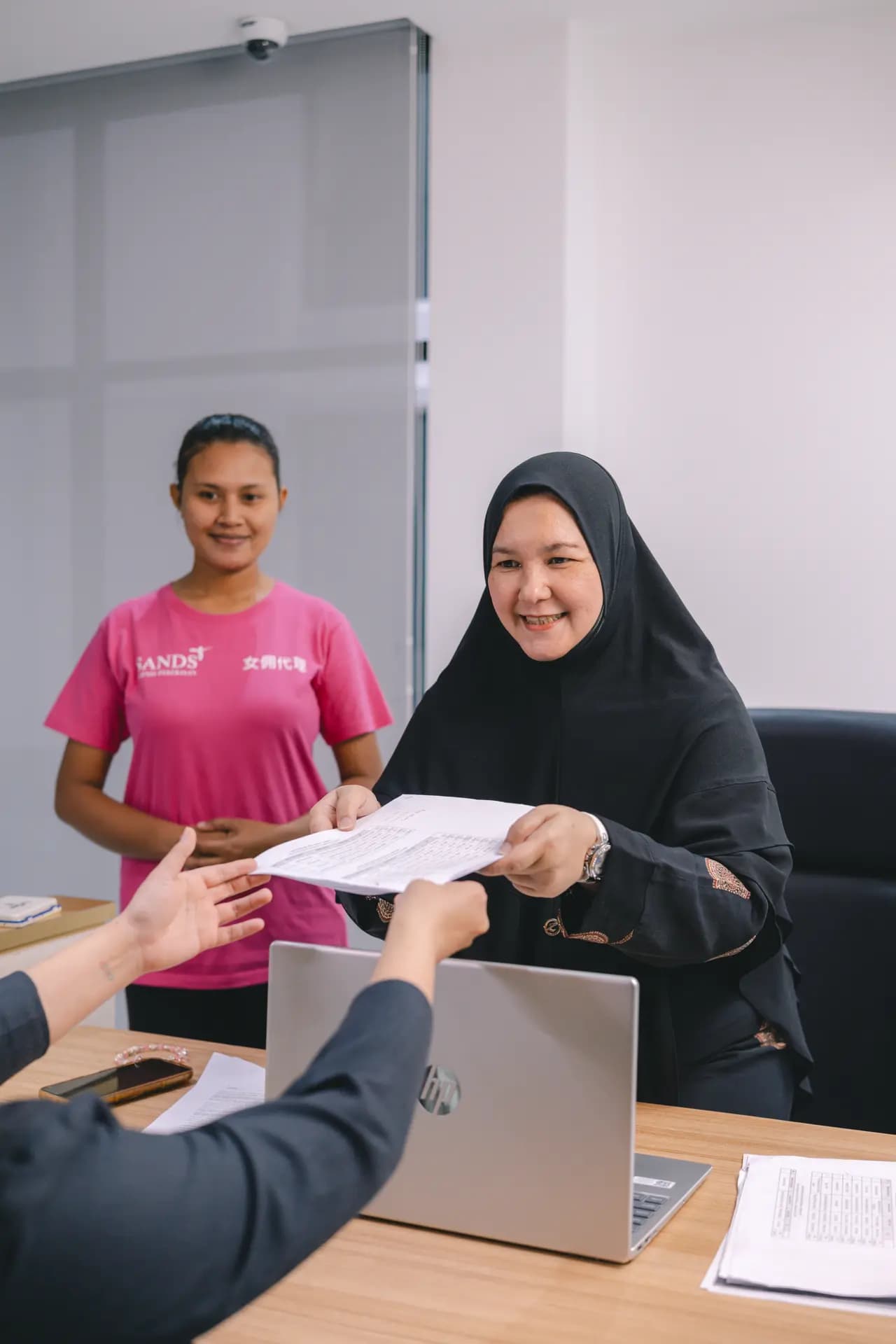 Staff handing document to client during consultation